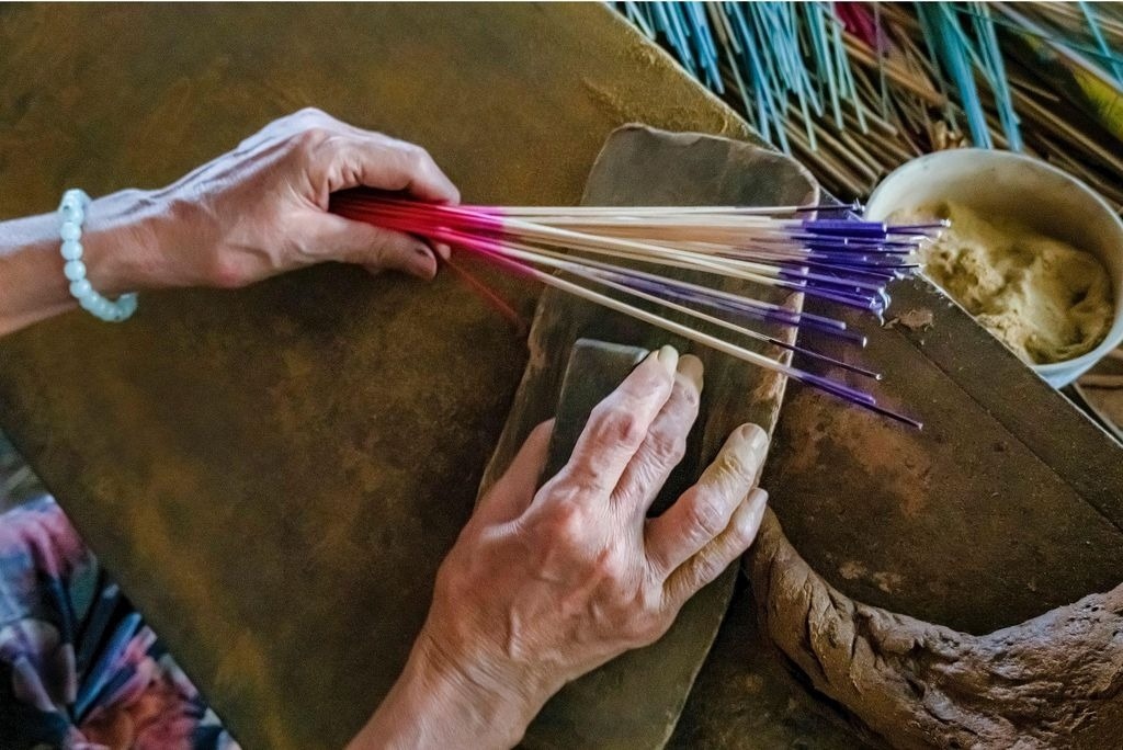 Artisan hands rolling incense sticks from floral waste